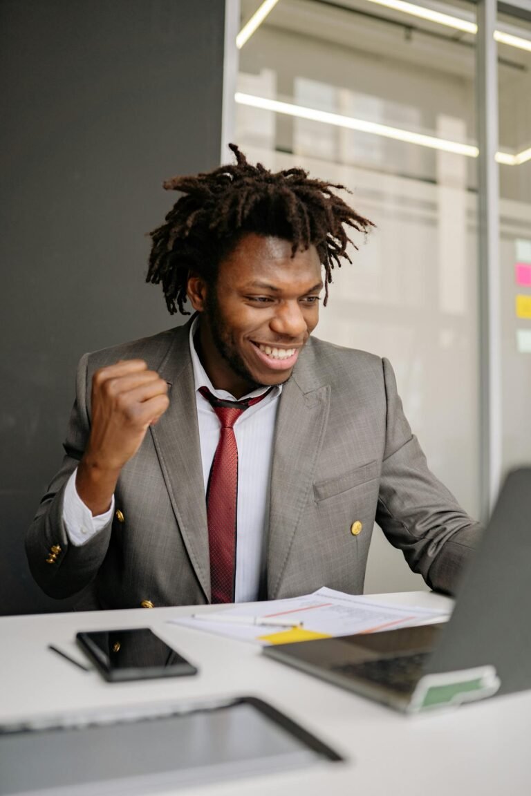 Excited businessman in suit celebrating success at his desk indoors.