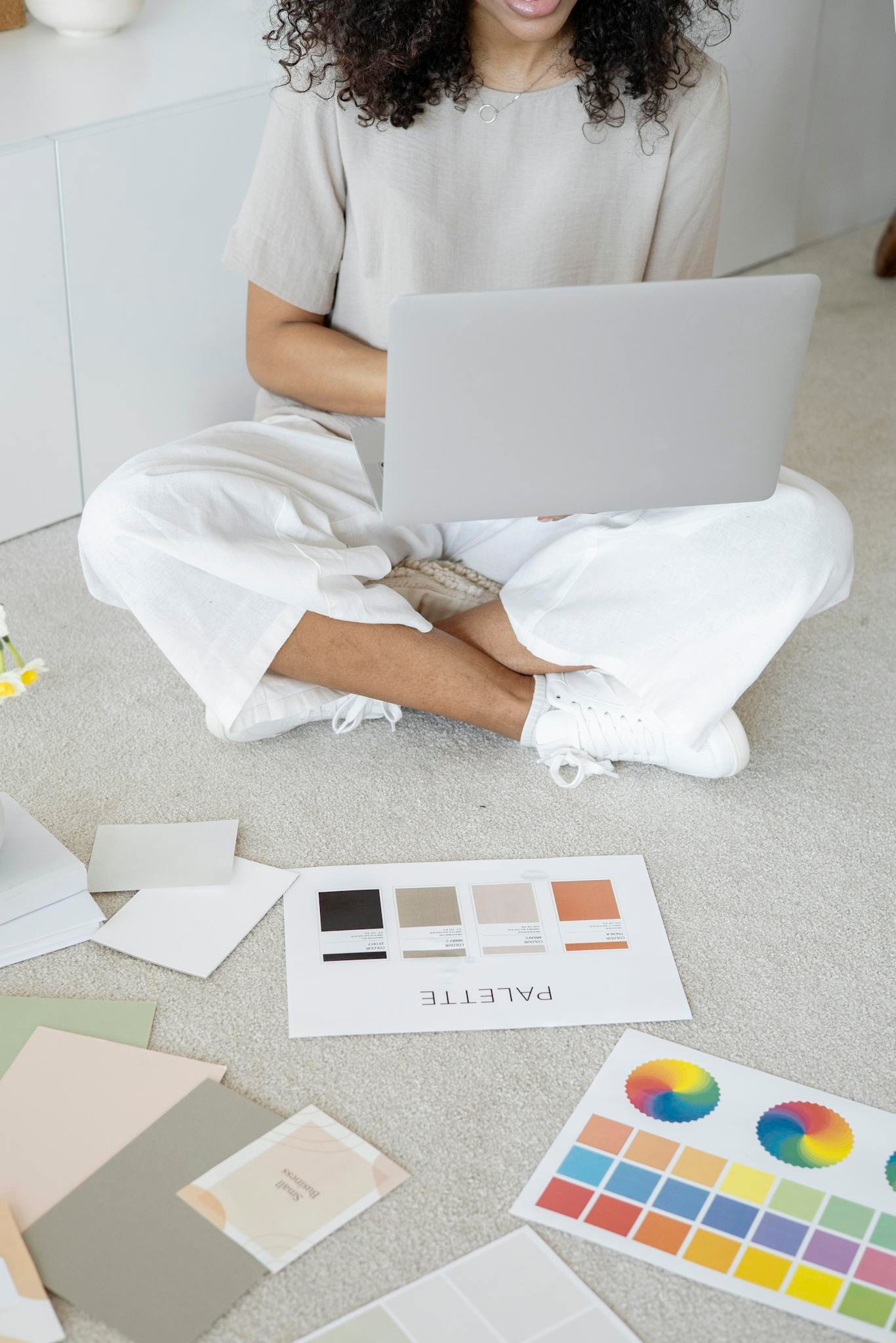 Young woman reviews color palettes for design project on laptop, sitting indoors.